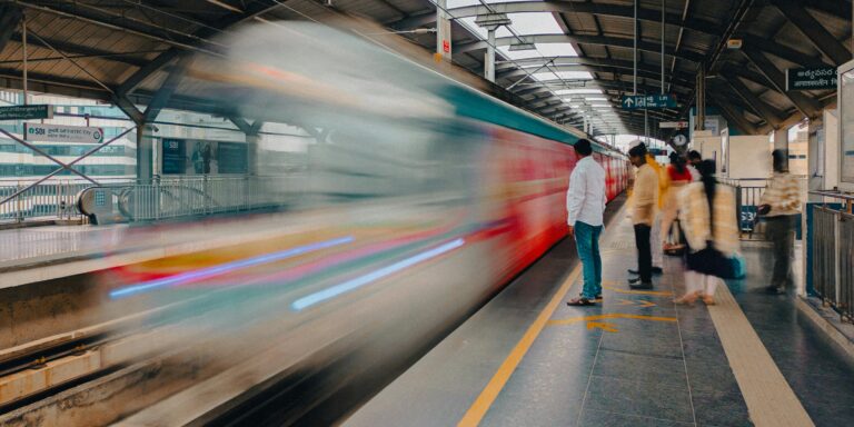Blurred metro train passing by commuters on a city station platform